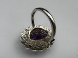 an image of a silver ring with a purple stone in the center