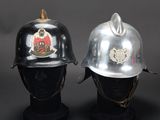 pair of firemen ' s helmets on display against a black background