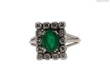 une image d'une bague avec une pierre verte entourée de diamants blancs