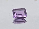 an amethorate cut purple stone sitting on top of a white surface