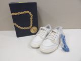 white sneakers with a gold chain on a table next to a box of jewelry