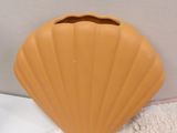 a shell shaped vase sitting on a bed next to a pillow