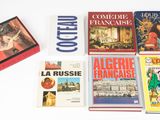 plusieurs livres posés sur une table blanche, sur laquelle se trouve une boîte rouge