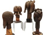 four wooden sculptures of elephants on stands on a white surface