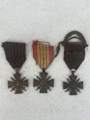 three medals and a cross are sitting on a white surface