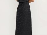 the back of a woman in a black dress standing in front of a white background