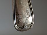 a silver spoon hanging from a string on a gray wall