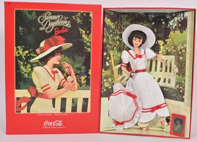 deux poupées Coca-Cola représentant des femmes en robe et chapeau, assises sur un banc
