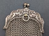 an antique silver metal chainmail purse on a black surface