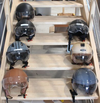 Plusieurs casques sont alignés sur une étagère en bois dans une pièce