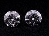 a pair of round cut diamonds on a black surface