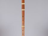 a wooden flute on a clear stand with a grey background