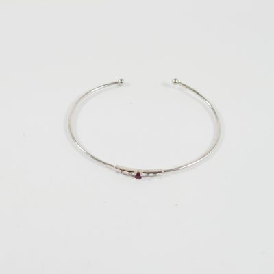 un gros plan sur un bracelet rigide en argent orné d'une pierre rouge