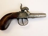 un vieux pistolet avec une poignée en bois sur une surface blanche