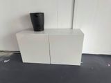a white cabinet with a black cup on top of it
