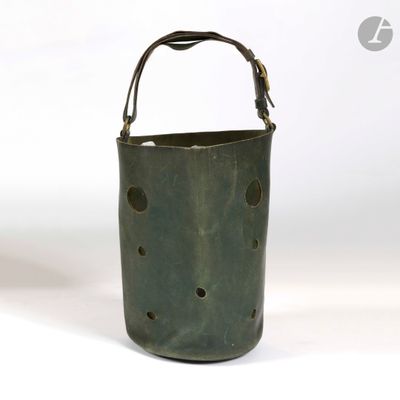 un vieux seau vert troué posé sur une surface blanche