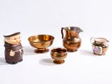 une petite figurine représentant un homme debout à côté d'un groupe de bols et de tasses