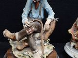 two figurines of a man sitting on a bench