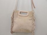 a white purse with fringes hanging on a wall
