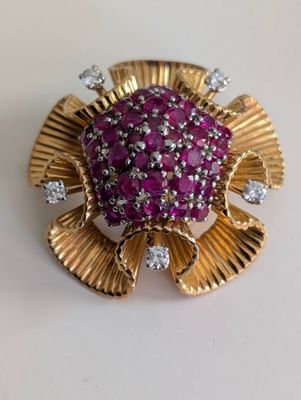 une image représentant une broche ornée de pierres roses et de diamants sur un fond blanc