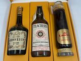 trois bouteilles d'alcool dans une boîte jaune posée sur une surface blanche