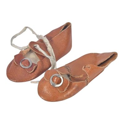 une paire de chaussures de bébé en cuir marron avec des boucles argentées, sur fond blanc