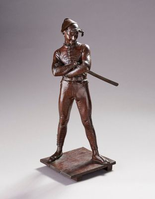 statue en bronze représentant un joueur de baseball tenant une batte, posée sur un socle en bois
