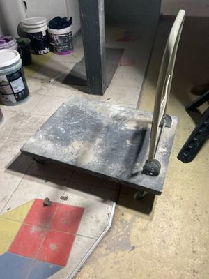 a metal object on the floor next to a paint can