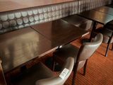 tables and chairs in a restaurant with a picture on the wall behind them