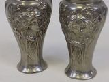 une paire de vases en argent ornés de visages sur un fond blanc