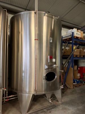 deux grandes cuves en acier inoxydable dans un entrepôt où se trouvent des cartons et des palettes