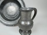 a silver vase and a silver plate on a table