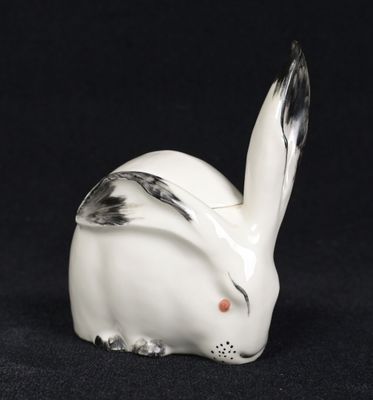 a white rabbit figurine sitting on top of a black surface
