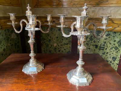 two silver candelabs sitting on a wooden table