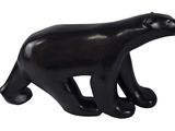 une figurine d'ours noir posée sur une surface blanche