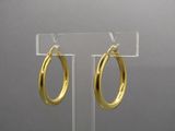 pair of gold hoop earrings on a clear acrylic stand