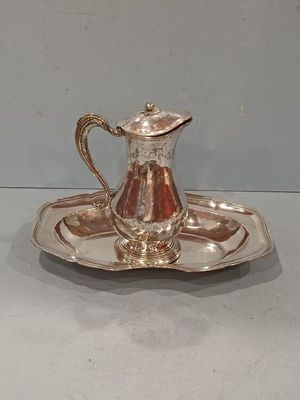 a silver plate with a silver pitcher on it