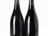 two bottles of wine sitting next to each other on a white surface
