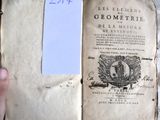 une personne tenant un vieux livre sur lequel figurent des inscriptions