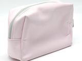 pink toiletry bag with zipper on white background with copy space