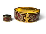 un bracelet doré et rouge et une bague posés sur un fond blanc