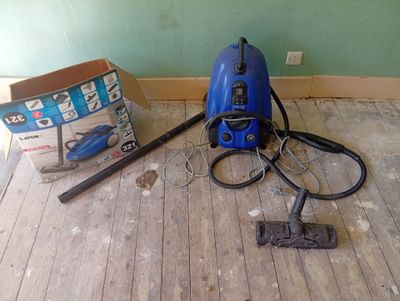 a blue vacuum sitting on the floor next to a box