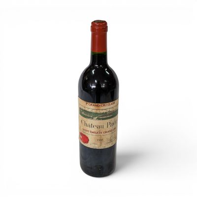 an old bottle of red wine sitting on top of a white surface
