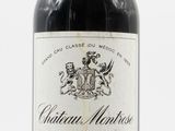 une vieille bouteille de vin rouge posée sur une table blanche