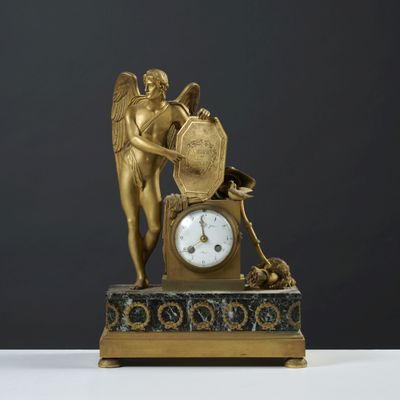 une statue en or représentant un ange, avec une horloge posée sur une table