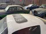 several old cars are parked in a garage with a brick wall in the background