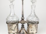 trois carafes en verre posées sur un plateau en argent orné d'une bougie