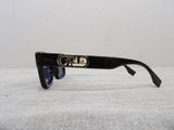 the sunglasses are black and have a gold emblem on the side