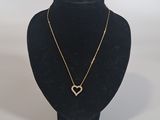a black mannequin with a gold heart necklace on it