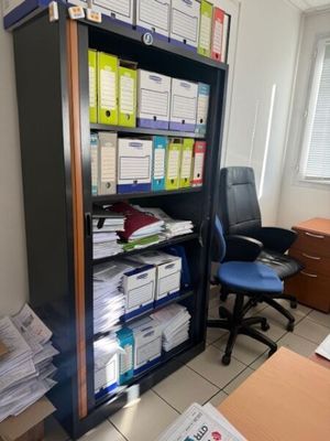 a desk with a chair and a bookcase full of papers